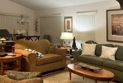 dated fabrics and naked windows, living room and dining room of an elevated Emerald model villa.